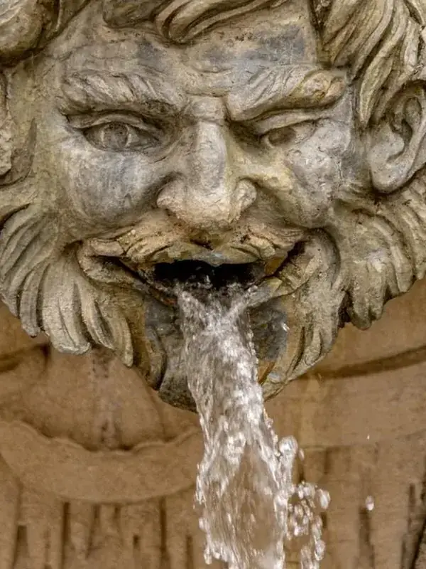 Stone fountain head with a stream full of separate drops