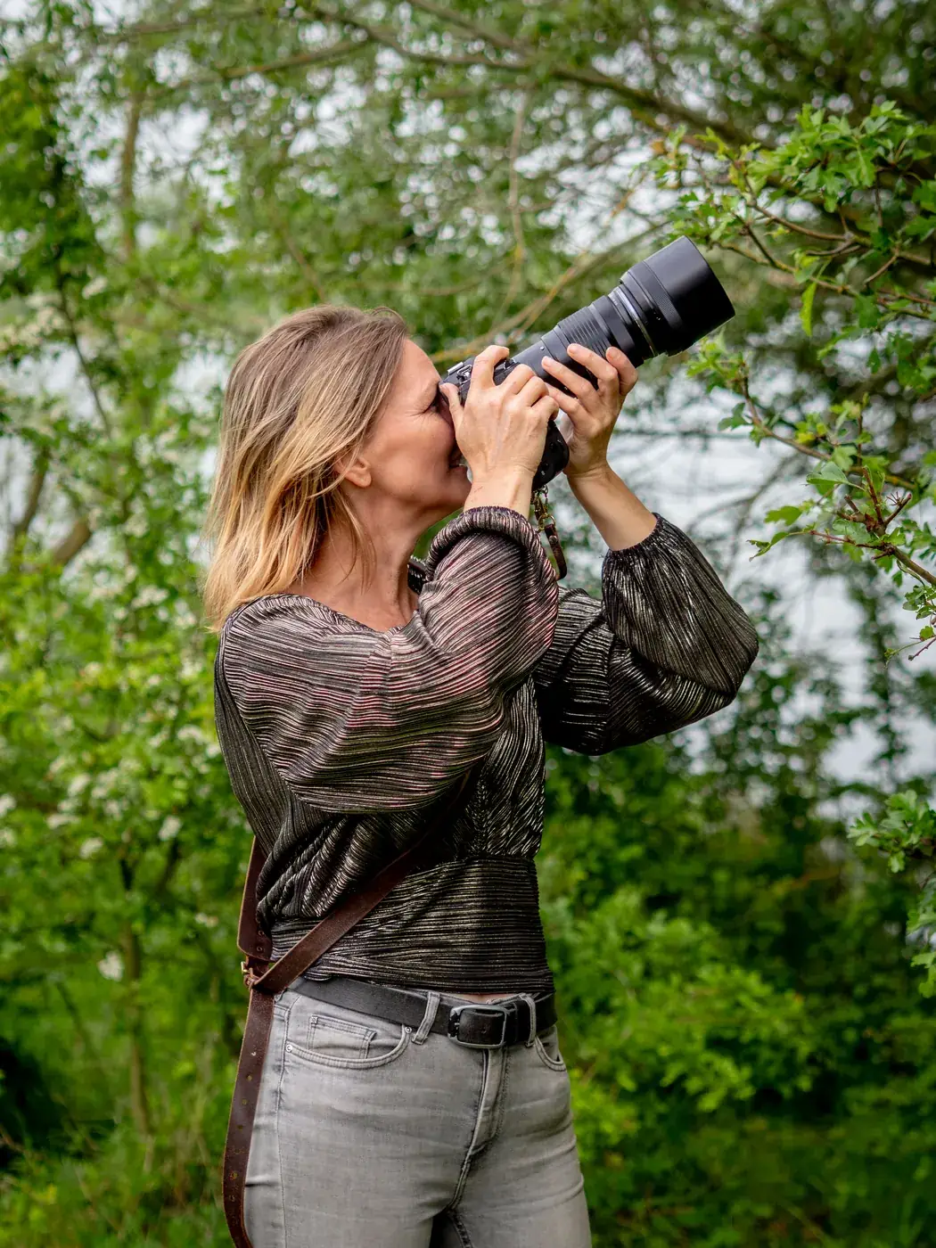 Linda Verweij photographing with her camera among green bushes